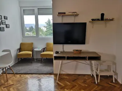 a living room with a tv on a wall with a table at Clock Tower Apartments in Podgorica