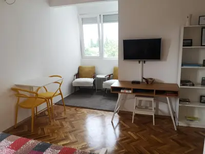 a living room with a desk with a television and chairs at Clock Tower Apartments in Podgorica