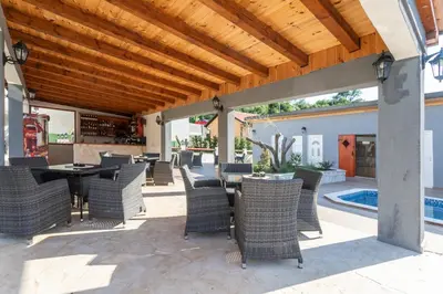 a patio with wicker chairs and tables and a wooden ceiling at Resort Bevilacqua in Budva
