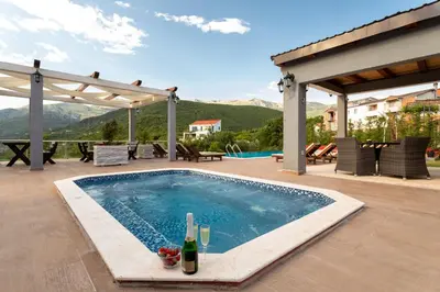 a swimming pool with a table and a bottle of wine at Resort Bevilacqua in Budva