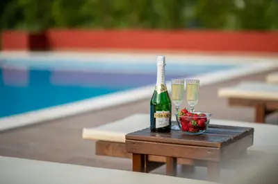 a bottle of champagne and glasses on a table next to a pool at Resort Bevilacqua in Budva