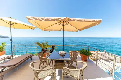 a table and chairs on a balcony with the ocean at Vila Dora in Dobra Voda
