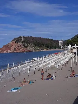 a group of people on a beach with chairs and umbrellas at Apartman Tatjana in Sutomore