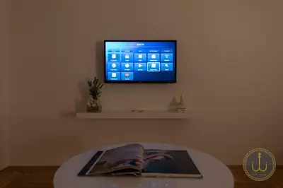 a flat screen tv on a wall with a table at Ancora 3 in Budva