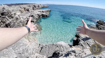 a person standing on a cliff with their hands up at Ancora 3 in Budva