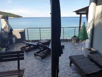 a patio with a view of the ocean with benches at Holiday House Kruce in Ulcinj