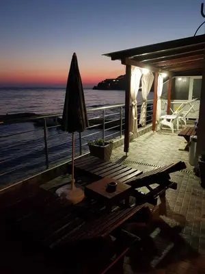 an umbrella and a table on a deck with the ocean at Holiday House Kruce in Ulcinj