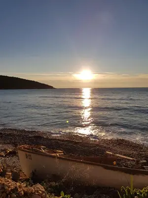 a boat sitting on the beach with the sun setting at Holiday House Kruce in Ulcinj