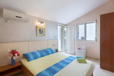 a bedroom with a bed with blue pillows and a window at Vila Hortenzija in Becici
