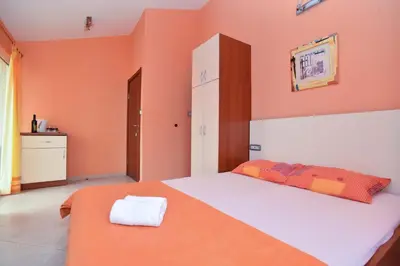 a bedroom with a bed with an orange wall at Vila Hortenzija in Becici