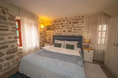 a bedroom with a bed and a stone wall at Antika Guesthouse in Kotor