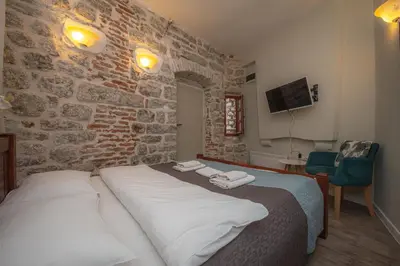 a bedroom with a bed and a brick wall at Antika Guesthouse in Kotor
