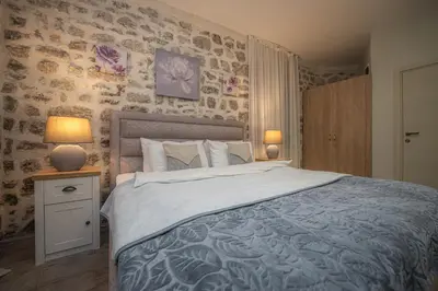 a bedroom with a large bed and two lamps on a table at Antika Guesthouse in Kotor