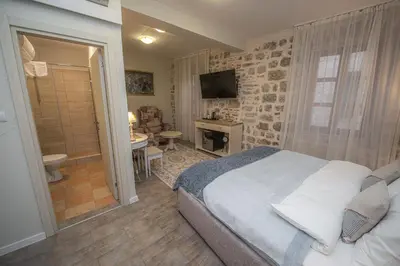 a bedroom with a large bed and a bathroom at Antika Guesthouse in Kotor