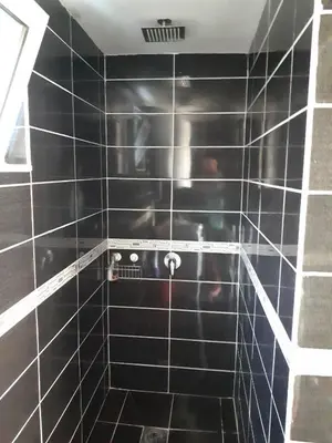 a black tiled bathroom with a black tile wall at Strandhaus Adria in Ulcinj