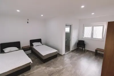 a bedroom with two beds and a chair at Strandhaus Adria in Ulcinj