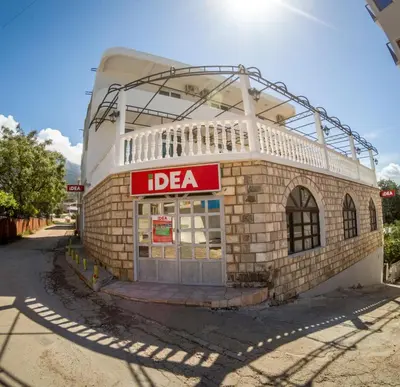 a building with a red sign on the side of it at Queen Apartments & Rooms in Dobra Voda