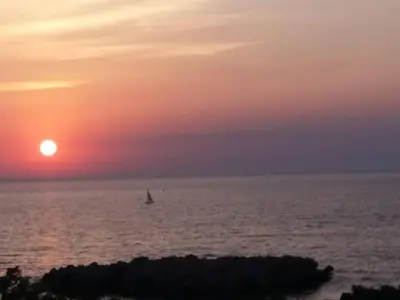 a sail boat in the ocean at sunset at Queen Apartments & Rooms in Dobra Voda