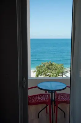 a view of the ocean from a balcony with a table and two stools at Queen Apartments & Rooms in Dobra Voda
