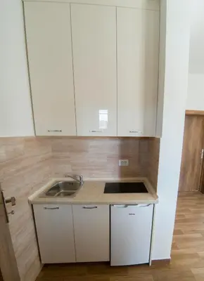 a kitchen with white cabinets and a sink at Queen Apartments & Rooms in Dobra Voda