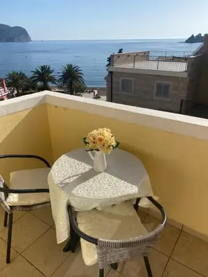 a table and chairs with a vase of flowers on a balcony at Miomir Perazic Apartments in Petrovac na Moru
