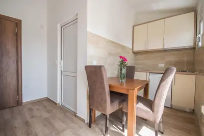 a kitchen with a wooden table with chairs and a vase of flowers at 3rooms,11 people in Bar