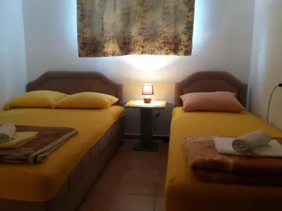 two beds in a room with a lamp on a table at Ori in Podgorica