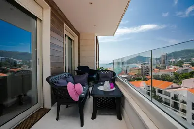 a balcony with two chairs and a table at Apartment with sea view in Rafailovici