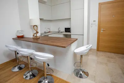 a kitchen with a counter and four bar stools at Apartment with sea view in Rafailovici