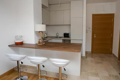 a kitchen with a counter and four stools at Apartment with sea view in Rafailovici