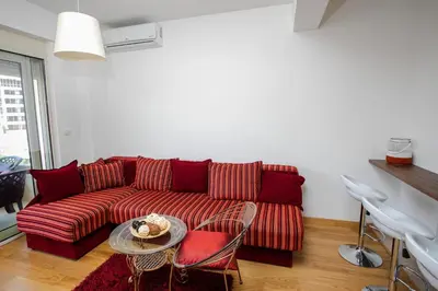 a living room with a red couch and a table at Apartment with sea view in Rafailovici