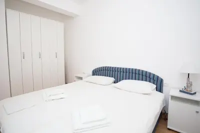 a white bedroom with a bed and a cabinet at Apartment with sea view in Rafailovici