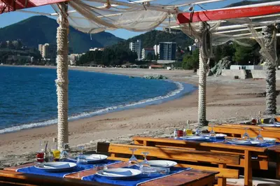 a group of tables with plates and glasses on a beach at Apartment with sea view in Rafailovici