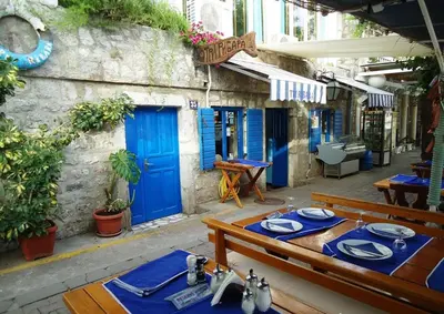a restaurant with blue doors and wooden tables and chairs at Apartment with sea view in Rafailovici