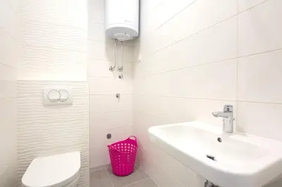 a white bathroom with a sink and a toilet at Chiron Apartments in Budva