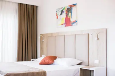 a bedroom with two beds with white sheets and an orange pillow at Villa Delux in Ulcinj