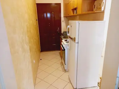 a small kitchen with a white refrigerator and a door at B4 in Budva
