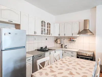 a white kitchen with a table and a refrigerator at Village experience - Skadar lake in Virpazar