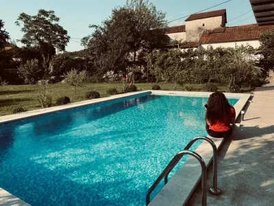 a woman sitting on a bench next to a swimming pool at Rustic village in Rijeka Crnojevića