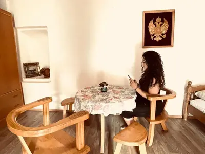 a woman sitting at a table looking at her cell phone at Rustic village in Rijeka Crnojevića