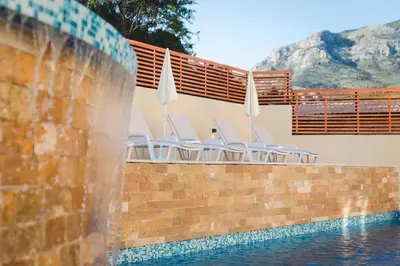 a pool with chairs and umbrellas on a brick wall at Villas Promis in Čanj