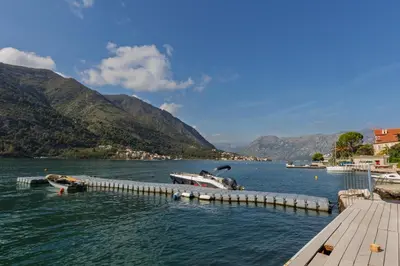a river with two boats docked at a dock at VerDi in Kotor