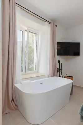 a large white bath tub in a room with a window at VerDi in Kotor