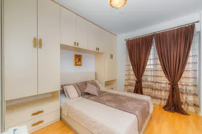 a small bedroom with a bed and curtains at HarMony apartment in Budva