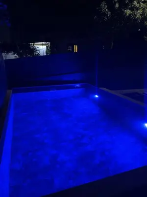 a swimming pool lit up at night with blue lights at Kevin-Talisa Villa in Bar