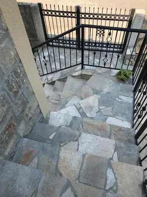 a stone walkway with a black rail and a fence at Sea forever in Petrovac na Moru