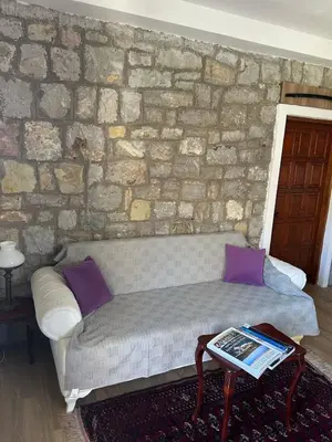 a living room with a couch and a stone wall at Sea forever in Petrovac na Moru