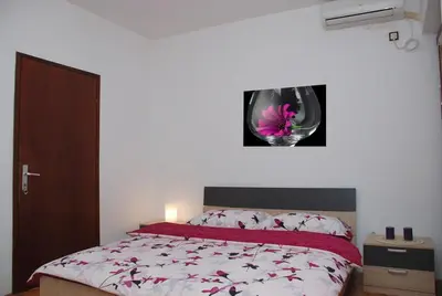 a bedroom with a bed with a flower on the wall at Apartments Svorcan in Budva