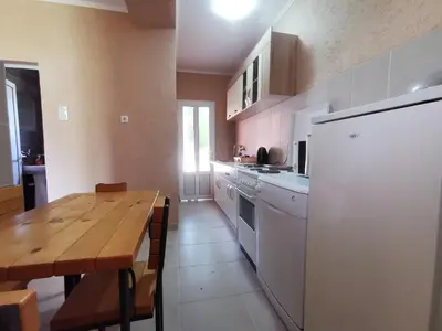 a kitchen with a wooden table and a white refrigerator at Bar-Apartman 2 in Bar