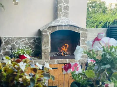 a stone fireplace in a yard with flowers at Apart dom Janković in Sutomore